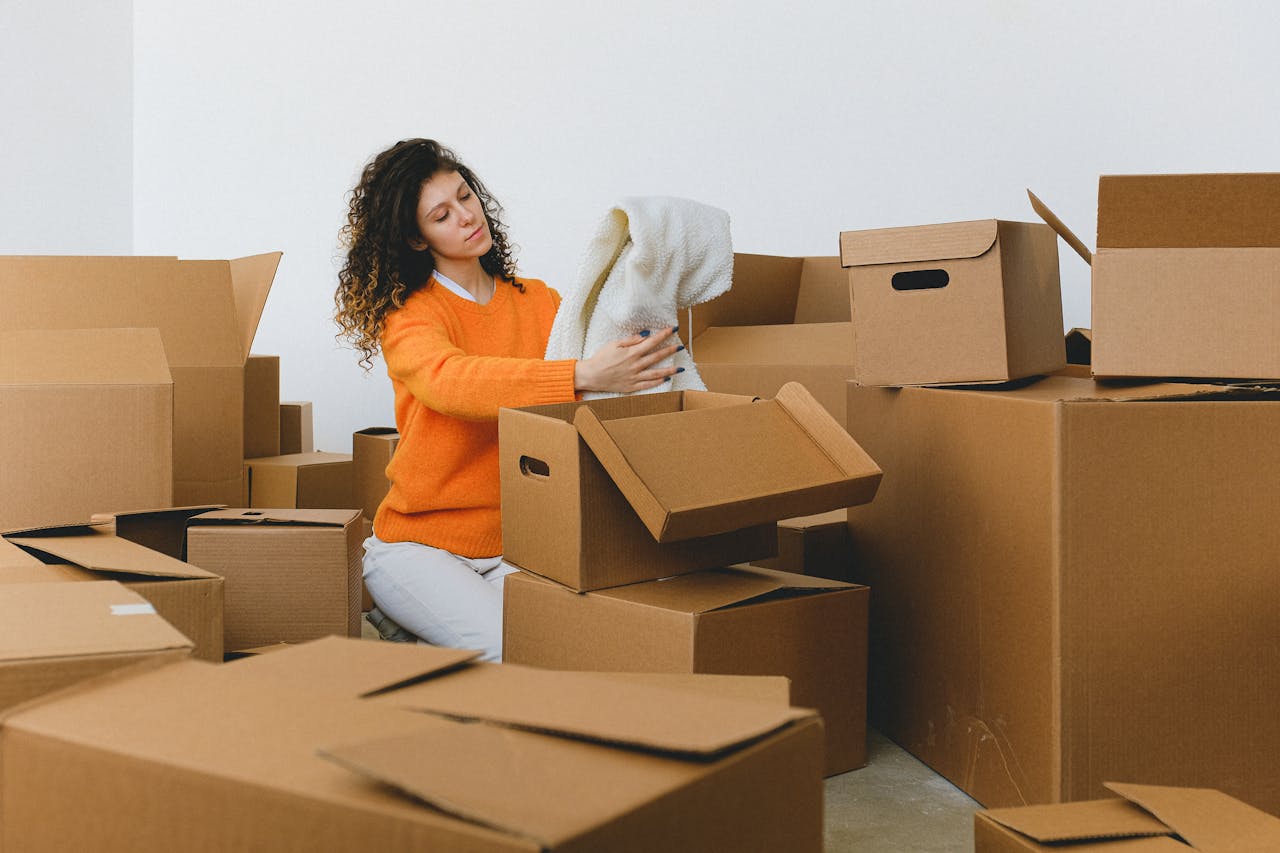 The Art of Drawing Readers In: Your attractive post title goes here Calm young relocating woman with curly dark hair in stylish sweater packing belongings into pile of cardboard boxes sitting on floor before moving into new apartment